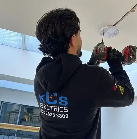 KCS Electrics Electrician is installing smoke detector device